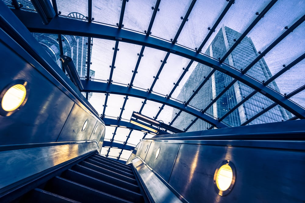 An interior view on an escalator, going up, with a glass wall above.