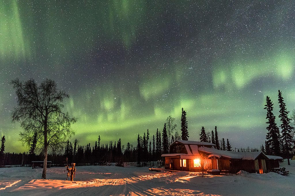 A picture of Husky Lodge at night with the aurora above in the sky.
